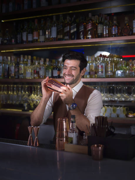 Bartender is making cocktail with talking customer at bar counter